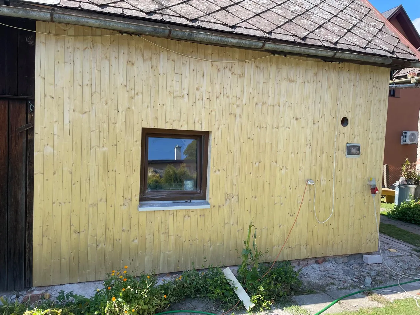 Boční stěna zahradního domku v Letohradě s dřevěným obkladem a oknem s parapetem